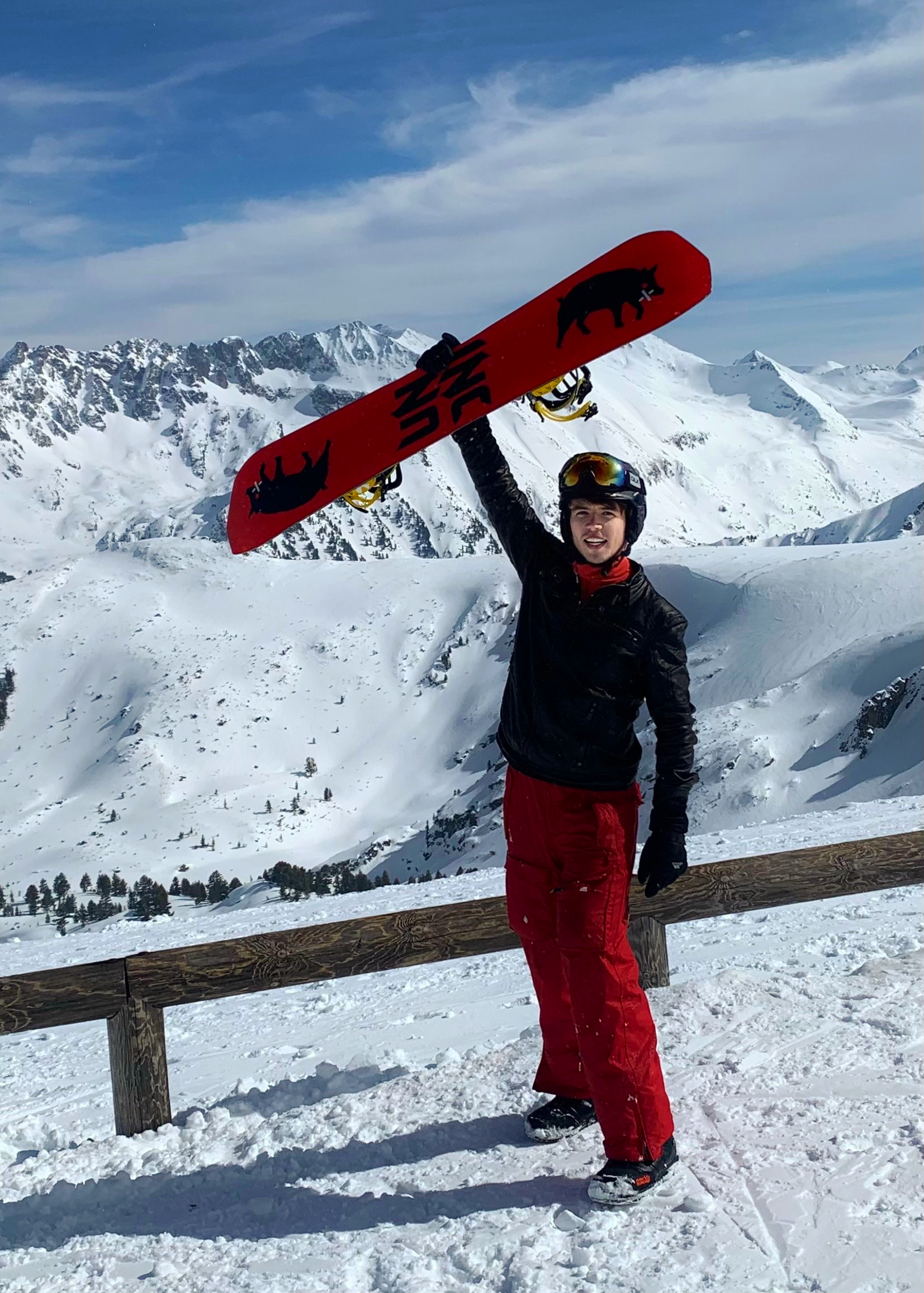 Holding a snowboard above my head on top of a snowy mountain